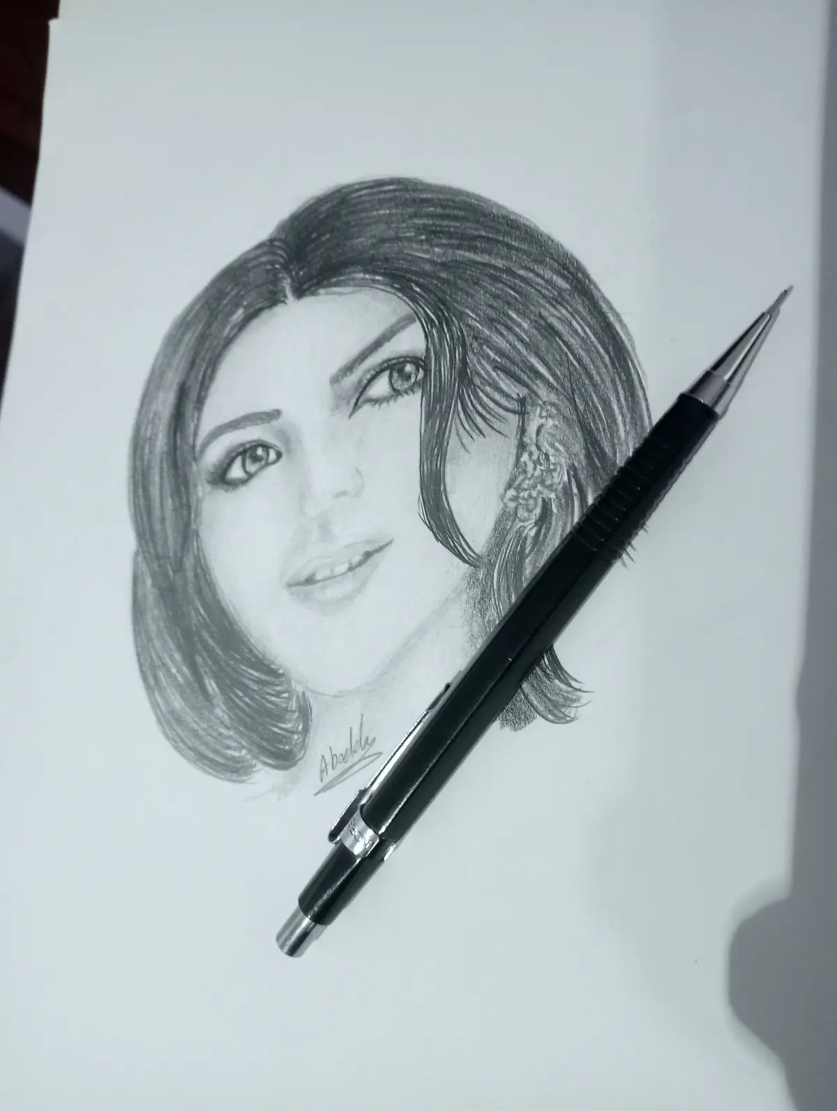A detailed pencil sketch of a woman's face with short hair and an ornate earring, signed 'Abadile' at the bottom, with a…