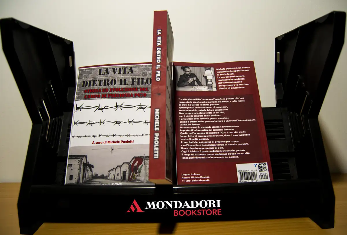 A book titled 'La Vita Dietro il Filo' by Michele Paoletti is displayed open in a black Mondadori Bookstore stand, showing…