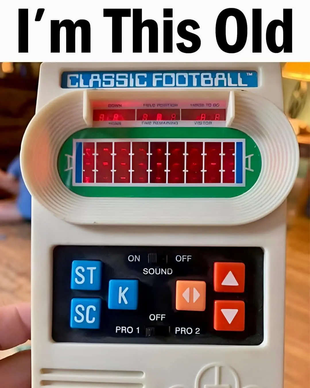 A close-up photo of a white handheld electronic game labeled 'CLASSIC FOOTBALL™' with a red LED display showing a football…