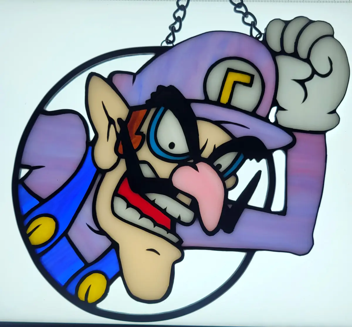 A stained-glass pendant depicts the video game character Wario with an angry expression, wearing his signature purple hat…