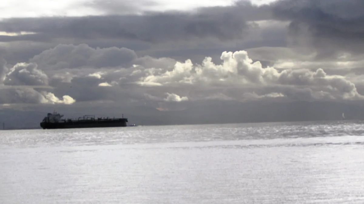 A large cargo ship sails on a calm, gray ocean under a dramatic, cloudy sky. The overlaid text reads 'i'm not crying, you're…