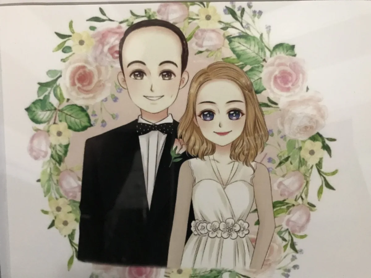 An anime-style wedding portrait shows a man in a tuxedo and a woman in a white dress, framed by pink and yellow flowers. The…