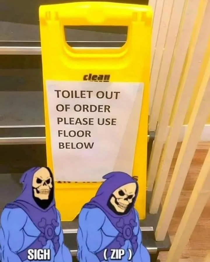 A yellow 'clean' floor sign with a white paper notice reading 'TOILET OUT OF ORDER PLEASE USE FLOOR BELOW' stands in a…