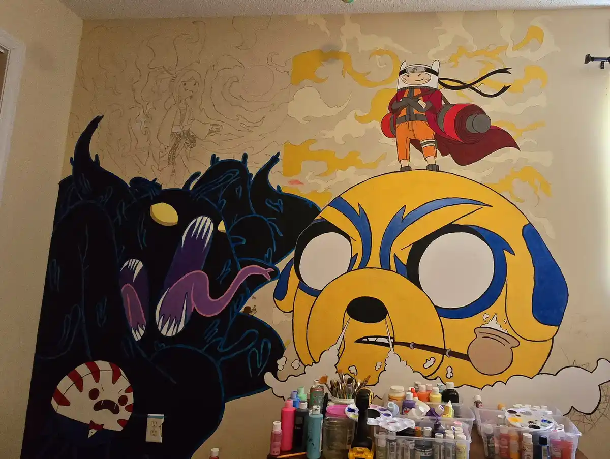 A large, unfinished wall mural depicts Finn from Adventure Time with a giant, angry face, while Jake the Dog is shown as a…