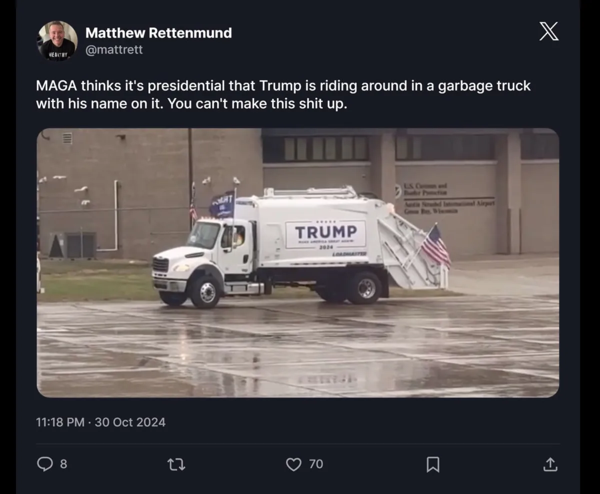 A white garbage truck with 'TRUMP 2024' and 'MAKE AMERICA GREAT AGAIN' written on its side is parked on a wet tarmac…