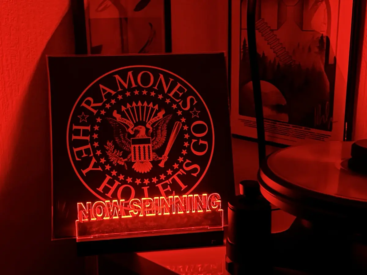 A red-lit decorative plaque displays the Ramones band logo, which is a parody of the U.S. Great Seal featuring an eagle…