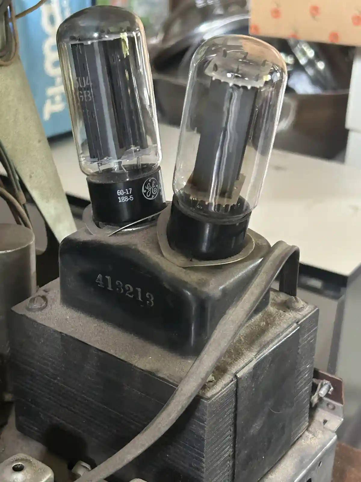 A close-up photo shows two vintage vacuum tubes mounted on a dusty, black metal chassis with the number '413213' stamped on…