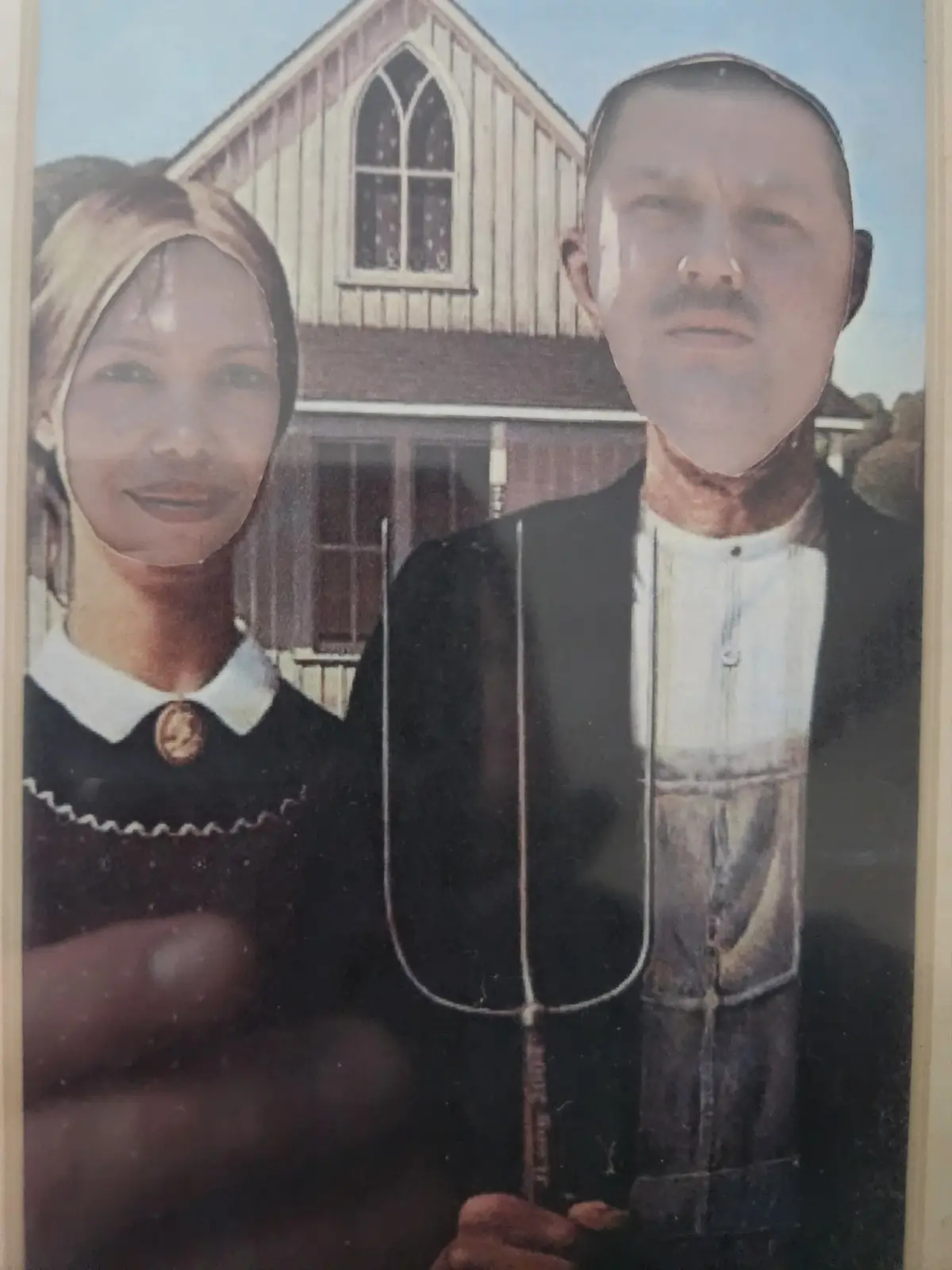 A vintage-style photo shows a man and woman dressed in Amish-style clothing standing in front of a wooden church with a…