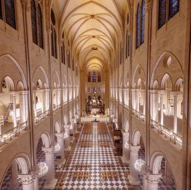 a high-angle photograph of a grand, empty cathedral interior with vaulted ceilings, arched windows, and a checkered floor…