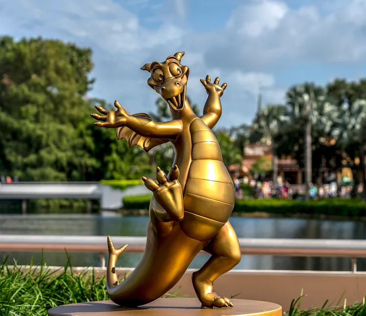A golden statue of the animated dragon character from Disney's 'Mulan' is posed cheerfully with arms raised and one leg…