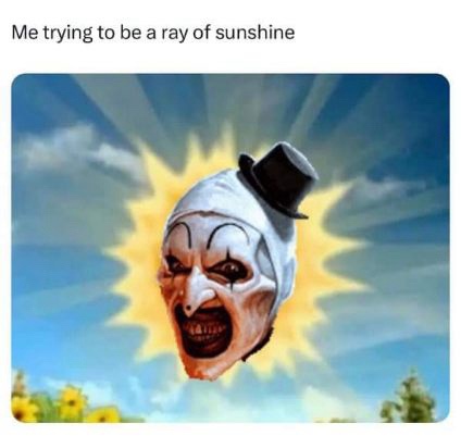 A distorted, grinning clown face wearing a small black top hat is superimposed over a bright yellow sunburst against a blue…