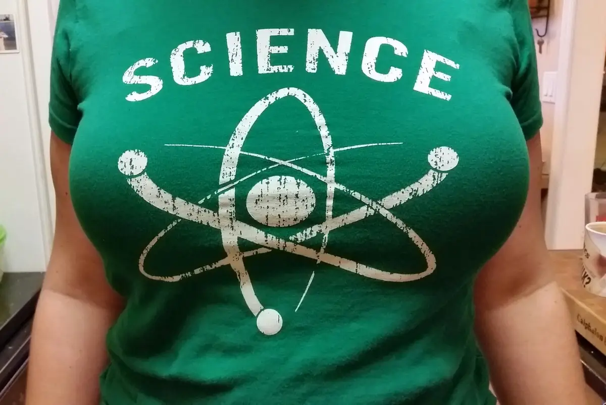 A person wears a green t-shirt with the word 'SCIENCE' in large white distressed letters above a stylized white atomic…