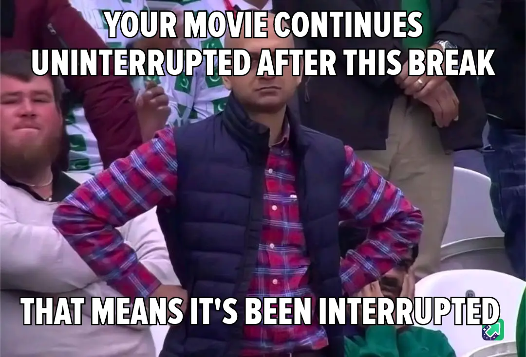 A man in a red plaid shirt and black vest stands with hands on hips in a stadium, looking annoyed. Text overlaid at the top…