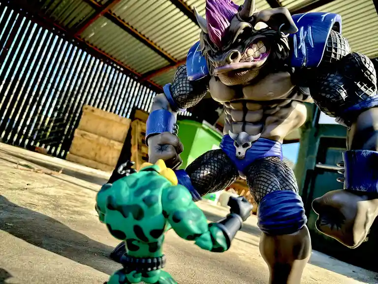 A large, muscular, bull-headed action figure with purple hair and blue armor looms over a smaller green, spotted action…