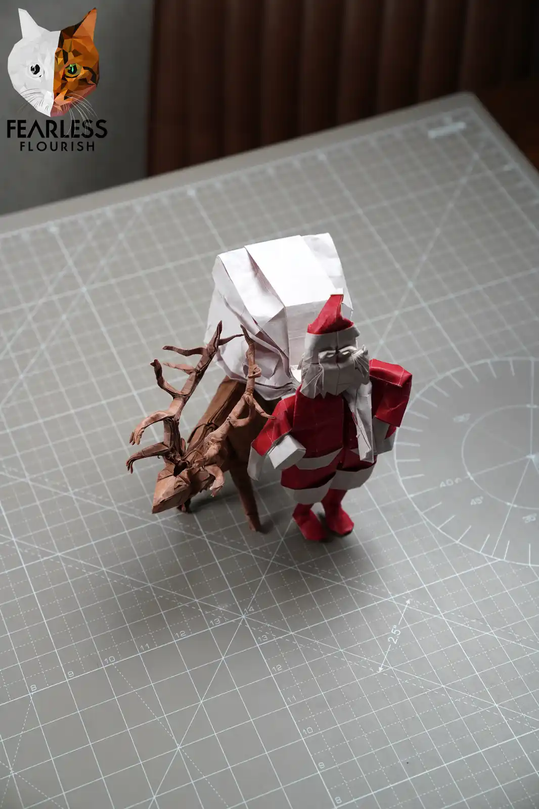 An origami Santa Claus figure in red and white, carrying a large white paper sack, stands beside an origami reindeer on a…