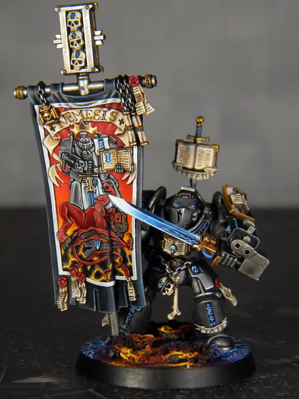 A highly detailed, painted miniature of a dark, armored warrior holding a large banner labeled 'NEMESIS' featuring a demonic…