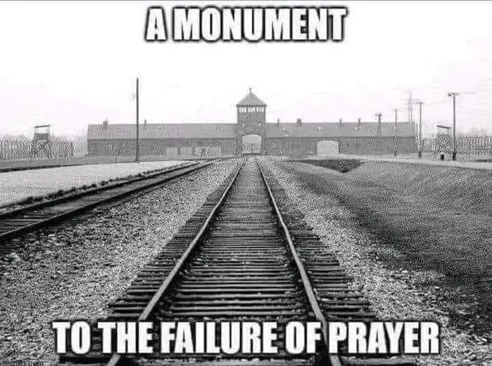 A black and white photo shows railroad tracks leading directly toward the main gate of the Auschwitz concentration camp…