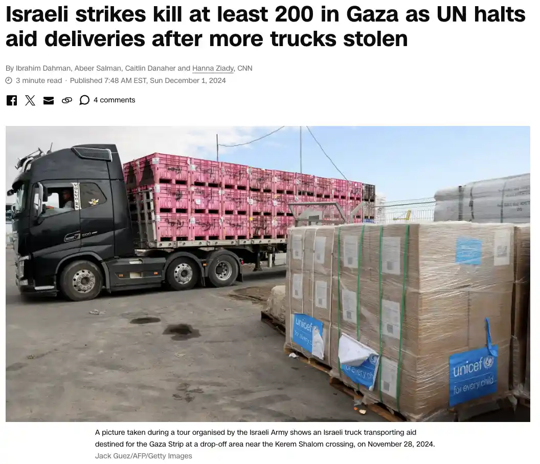 A black semi-truck loaded with pink crates is parked next to large pallets wrapped in plastic and labeled with UNICEF logos…