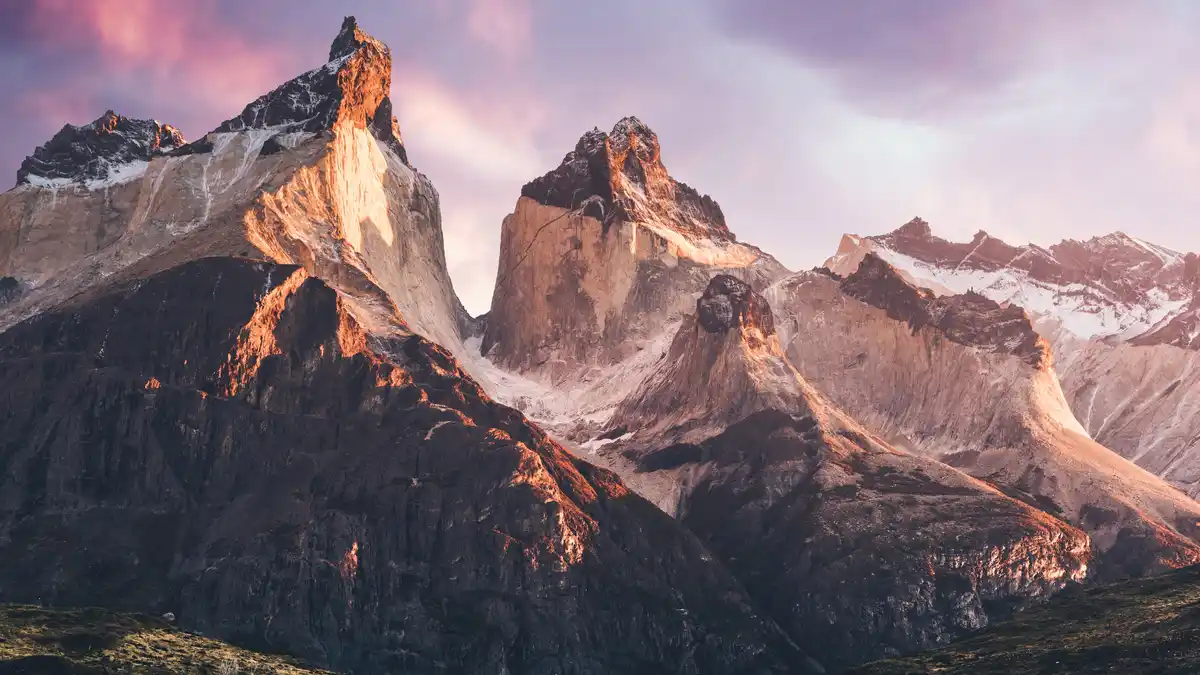 In Chilean Patagonia, the Cuernos del Paine mountains emerge from misty veil as the clouds clear, revealing their unique…