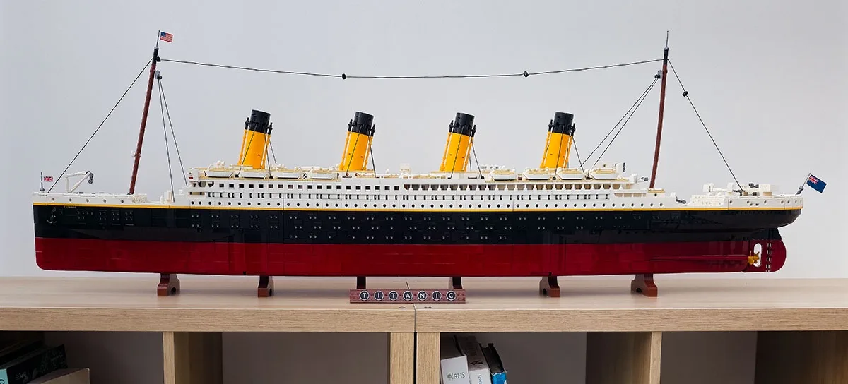 A detailed LEGO model of the RMS Titanic, featuring its iconic black and red hull, four yellow funnels, and white…