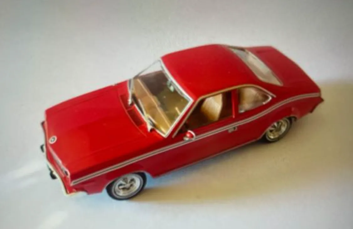 A red toy car model with silver trim and tan interior sits on a plain white surface. The overlaid text reads 'i'm not a car…