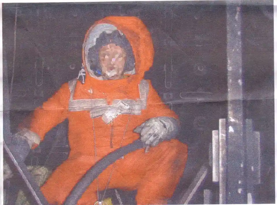 A person in an orange astronaut suit sits inside a spacecraft cockpit, gripping a control stick. Their face is pixelated…