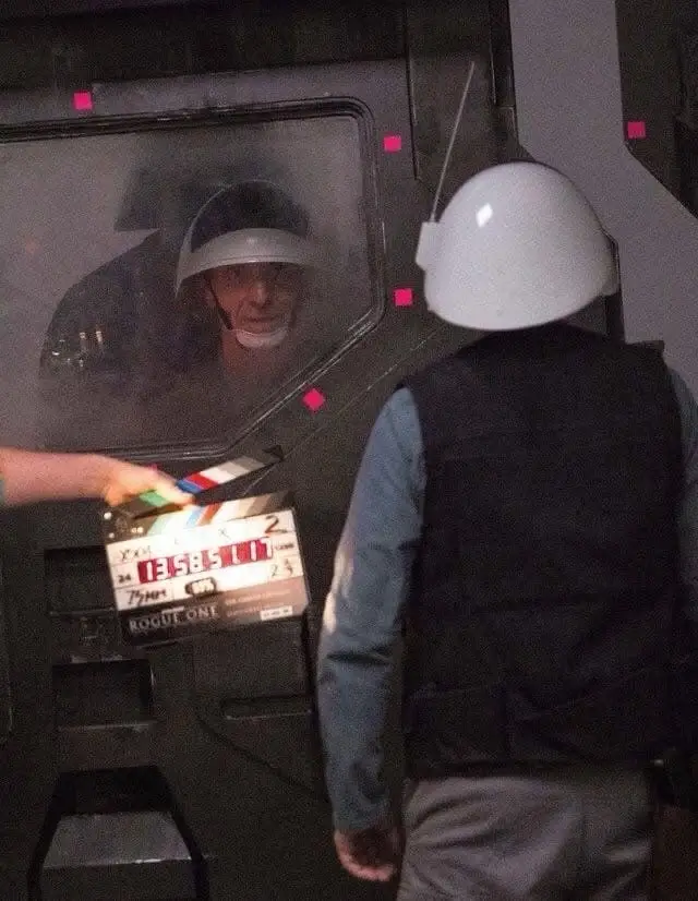 A behind-the-scenes photo from the movie 'Rogue One' shows a person in a white helmet and vest standing in front of a…