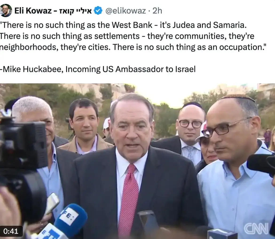 A screenshot of a tweet by Eli Kowaz showing a video clip of Mike Huckabee speaking to reporters outdoors. He is surrounded…