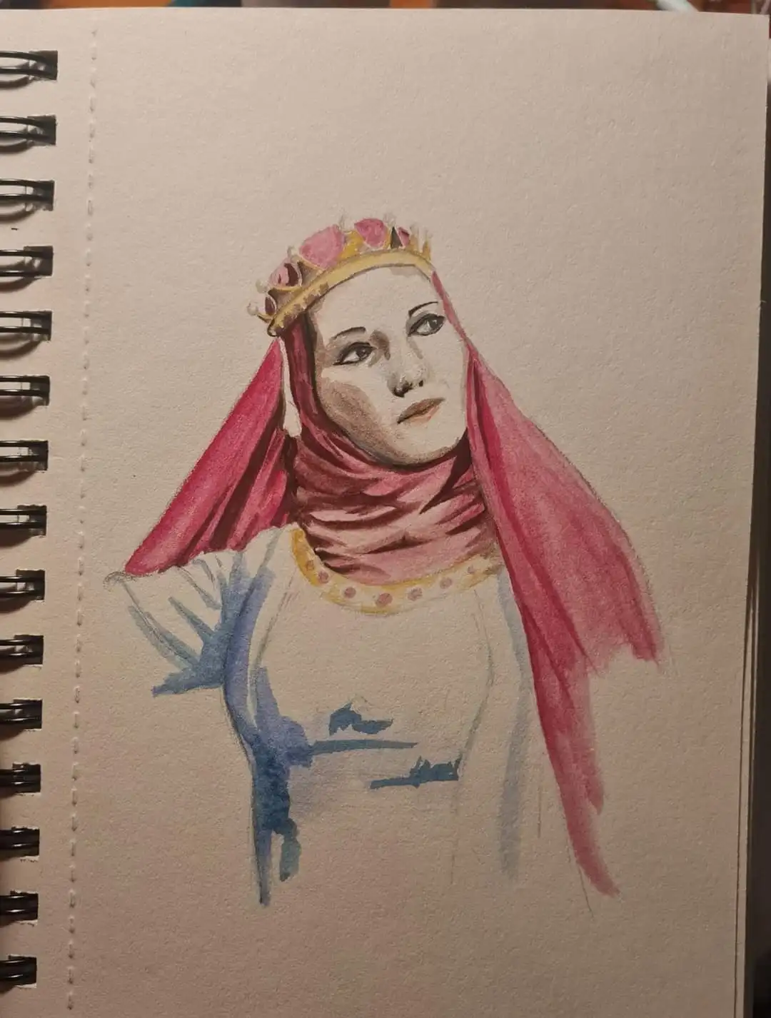 A watercolor drawing on spiral-bound notebook paper depicts a woman wearing a gold crown with pink jewels and a red hijab…