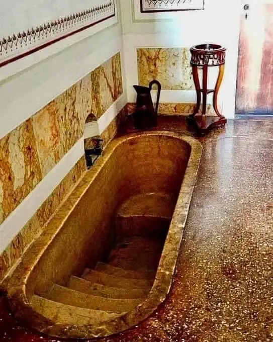 An ornate, marble-like bathtub with built-in steps is shown in a luxurious bathroom, but the overlaid text reads 'this is…