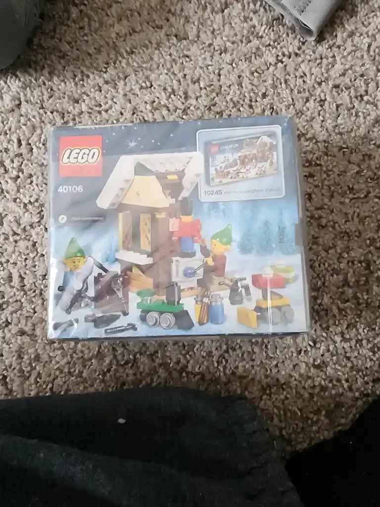 A sealed LEGO Creator set box (40106) shows a winter scene with elves and a cabin, but a small inset image on the right…