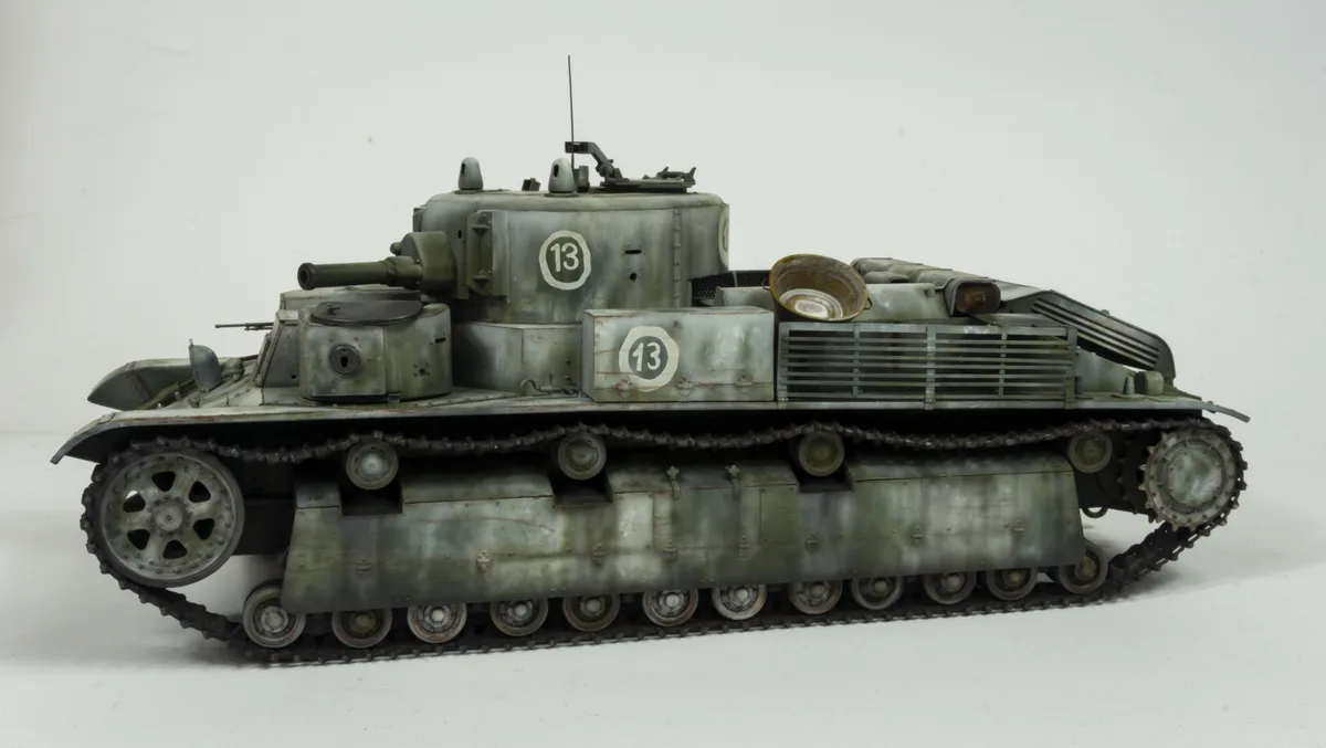 A detailed scale model of a military tank, painted in weathered green and gray, with the number '13' prominently displayed…