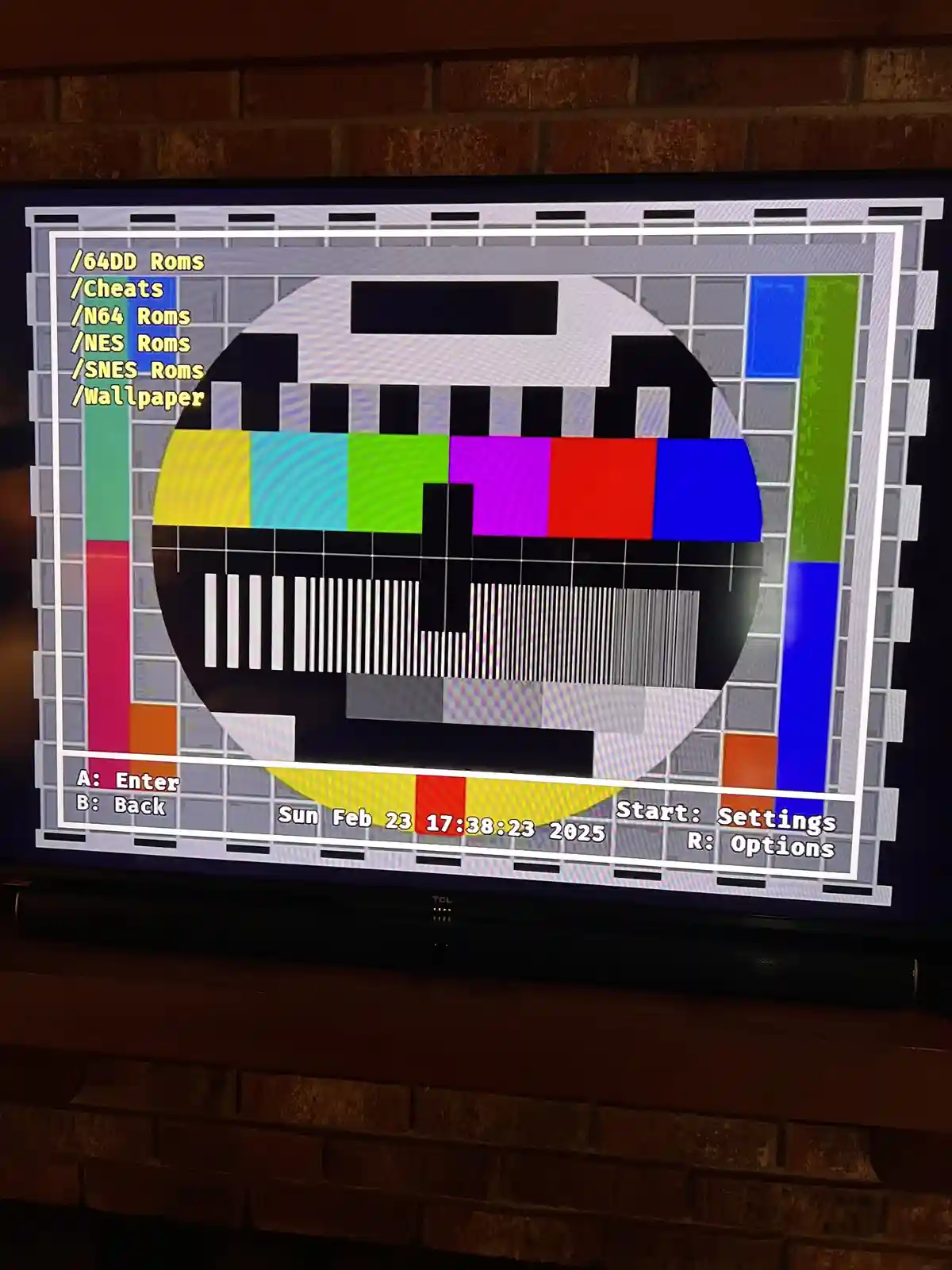 A television screen displays a retro-style video game menu overlaid on a classic television color bar test pattern. The menu…