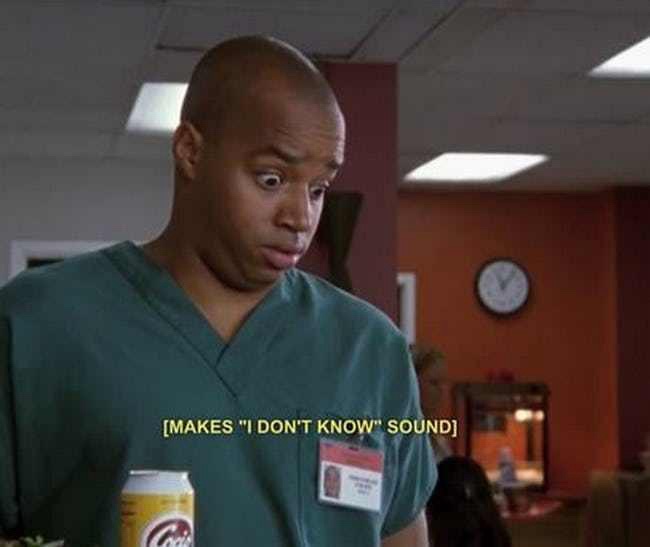 A man in green scrubs holds a can of Coors Light, looking confused and slightly disgusted. He has a name badge on his chest…