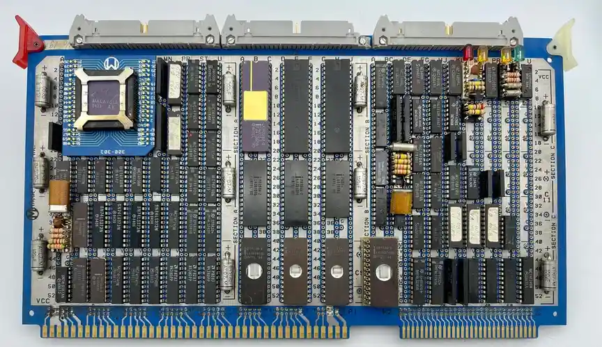 A close-up photo of a blue computer motherboard densely populated with black integrated circuits, resistors, capacitors, and…