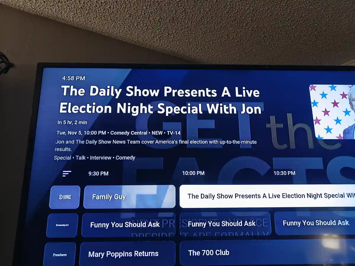 A TV screen shows a program guide listing 'The Daily Show Presents A Live Election Night Special With Jon' scheduled for…