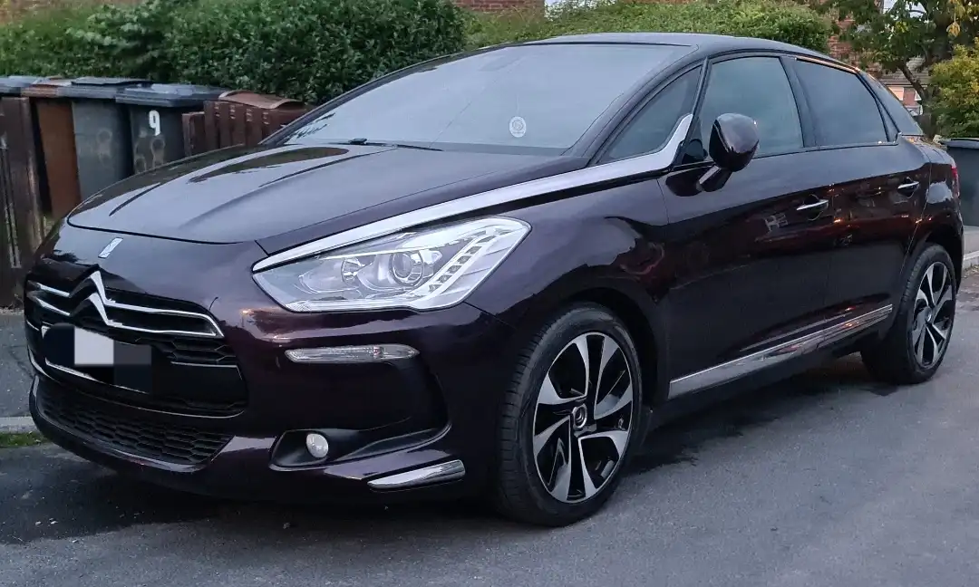 a dark purple citroën ds5 luxury crossover parked on a residential street, with chrome accents, stylish alloy wheels, and a…