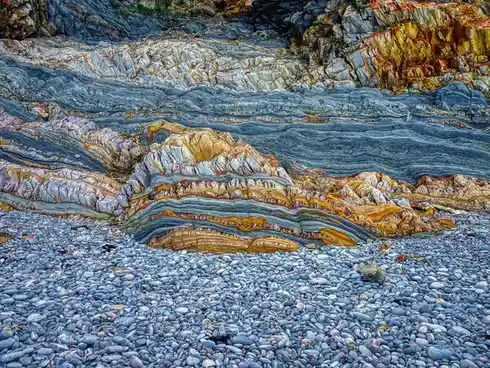 This is a photo of a colorful, layered rock formation on a pebble beach, with the text 'this is a photo of a colorful…
