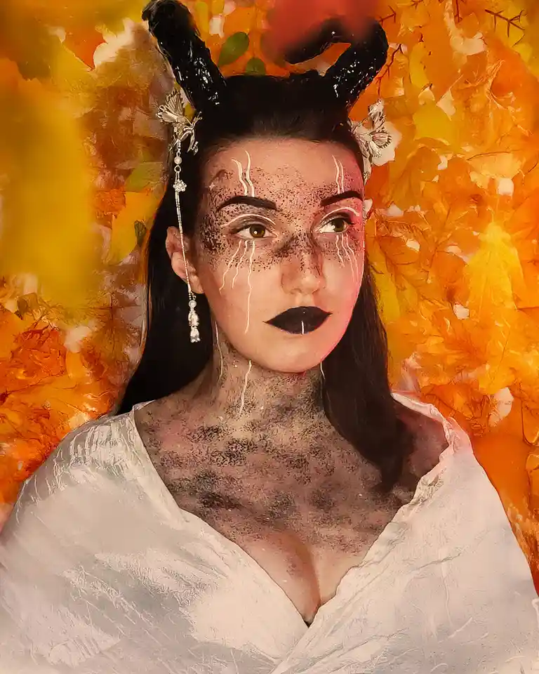 A person with dark horns, freckles, and white tear-like streaks down their face and neck, wearing a white garment, set…