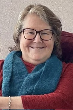 A smiling woman with glasses and a blue scarf sits in a red chair. Overlaid text reads 'i'm not a fan of the new policy'.