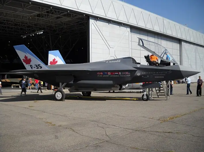 A grey F-35 fighter jet with 'Canada' and 'F-35 Joint Strike Fighter' written on its side, featuring a Canadian flag on its…