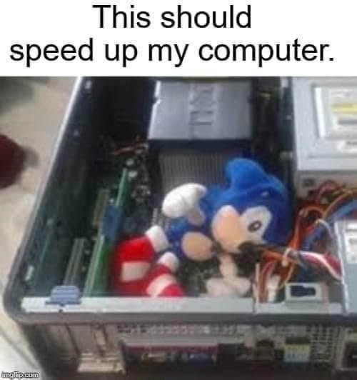 A plush Sonic the Hedgehog toy is stuffed inside an open computer case, sitting among the motherboard, cables, and other…