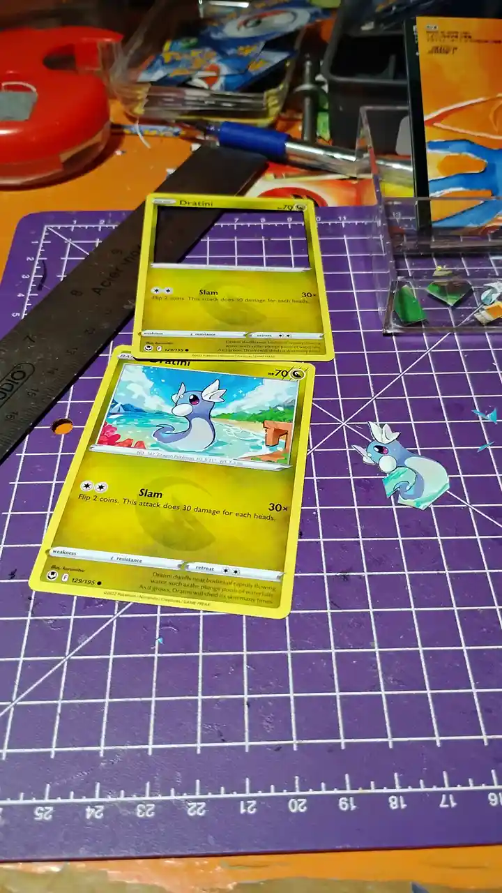 Two identical Pokémon TCG Dratini cards are shown on a purple cutting mat, one with its artwork intact and the other with a…