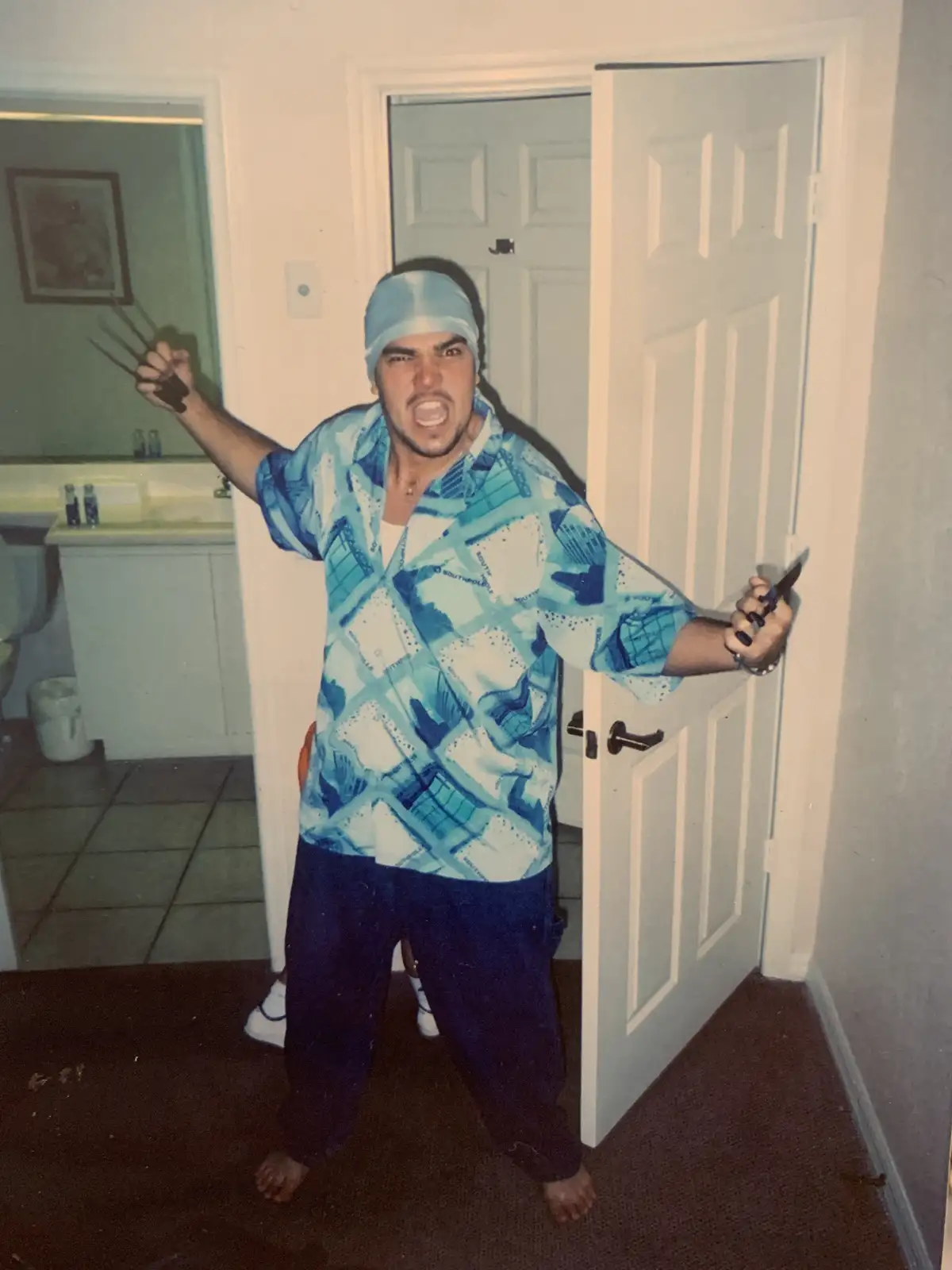 A man in a blue patterned shirt and surgical cap stands in a doorway, yelling aggressively while holding Wolverine-style…