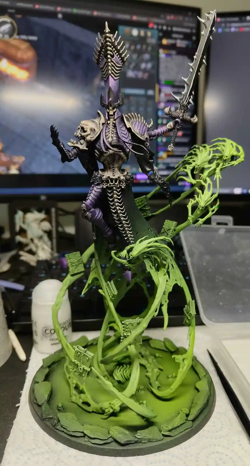 A highly detailed, painted miniature of a skeletal, purple-armored fantasy warrior wielding a spiked sword, standing atop a…