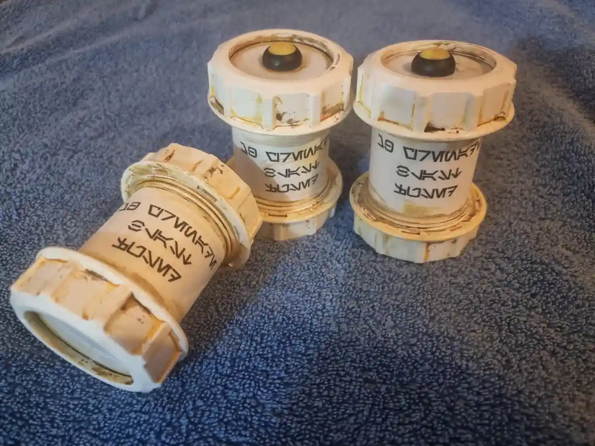 Three dirty, white plastic bicycle bottle cage mounts lie on a blue towel, each with reversed text that reads 'flipped' when…