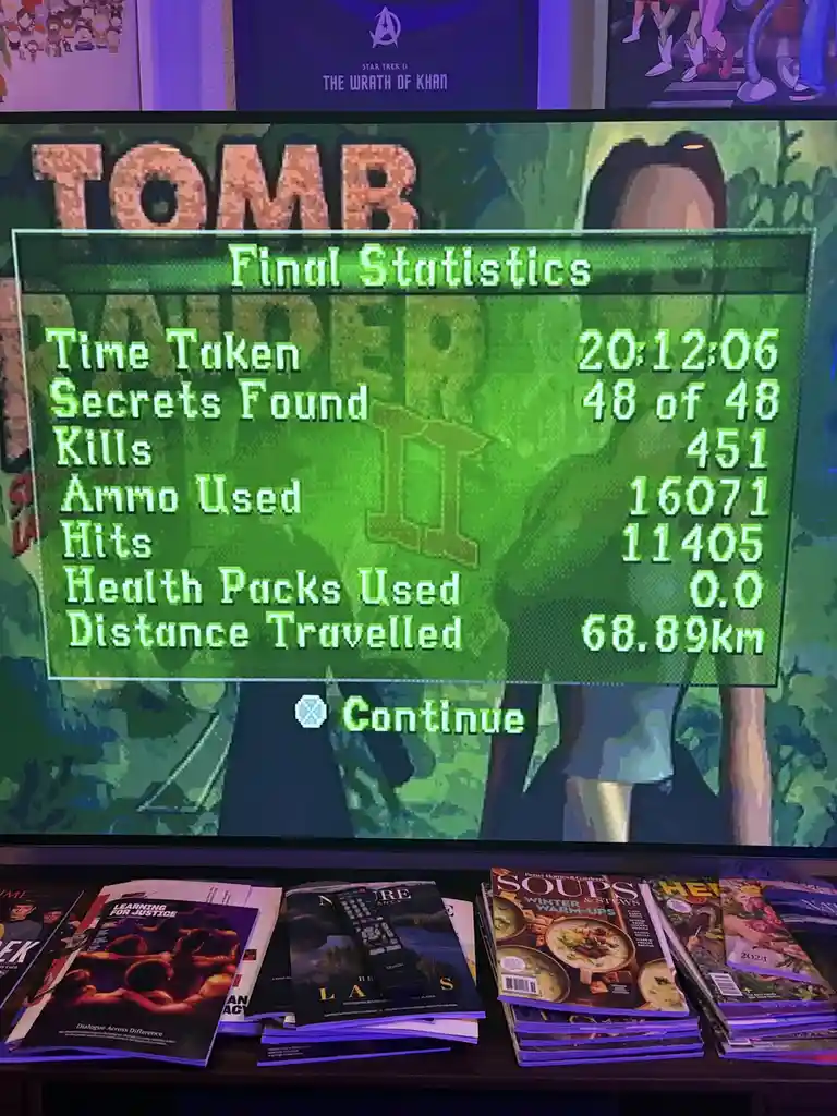 A photo of a TV screen displaying the final statistics from a Tomb Raider game, showing 451 kills, 16,071 ammo used, and 0…