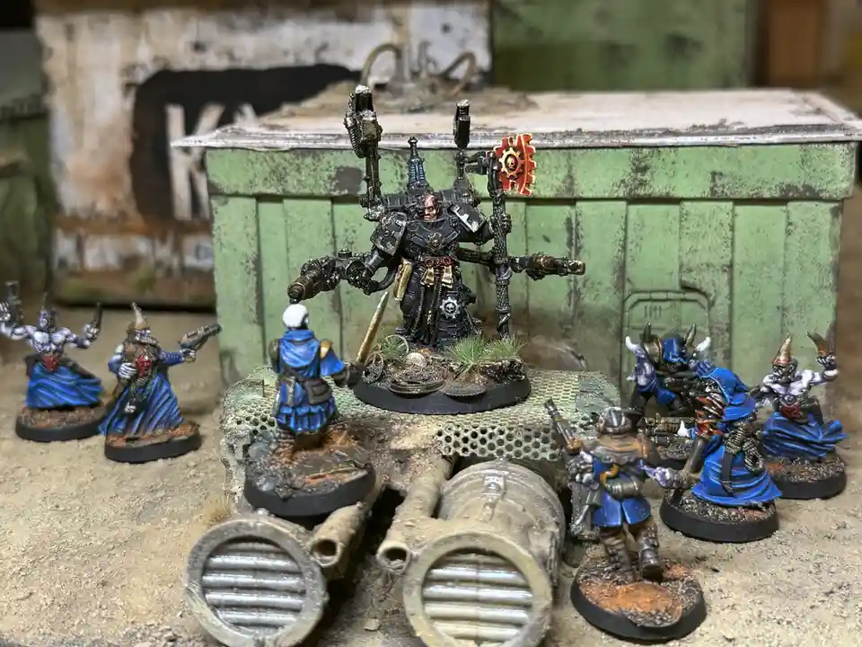 A photo of a collection of painted miniature figurines, including a large central armored figure with multiple weapons and a…