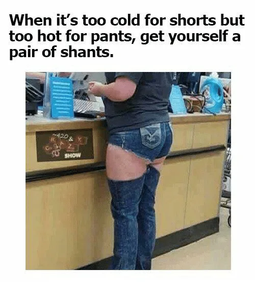 A person is standing at a store counter wearing a black t-shirt and denim shorts that are cut off at the thigh, revealing…