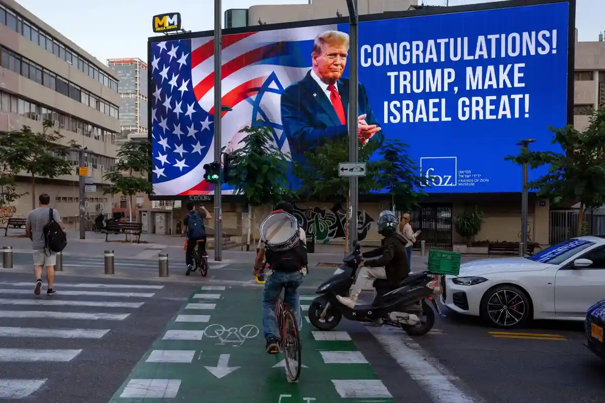 A large outdoor billboard in an urban setting displays a photo of Donald Trump with the text 'CONGRATULATIONS! TRUMP, MAKE…